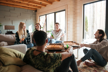 Group of people eating pizza and relaxing in living room