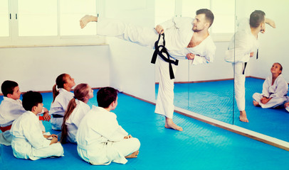 Male coach explaining new maneuvers to children