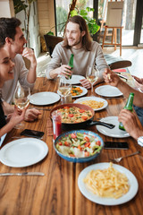 Group of cheerful friends eating and talking at the table