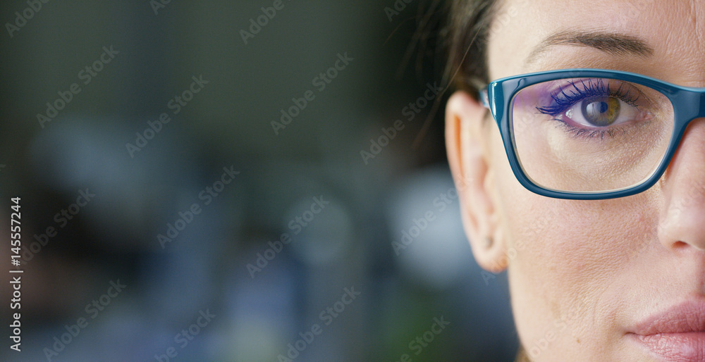 Wall mural portrait of a beautiful girl with glasses, with green eyes, shot close-up, on a blurred background. 