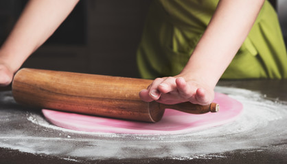 Woman using rolling pin preparing royal icing for cake decorating, hands detail