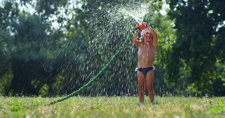 On a sunny hot day, a baby is playing with water and enjoying it very bathing with water. The baby is very happy and smiling because the water is cold.