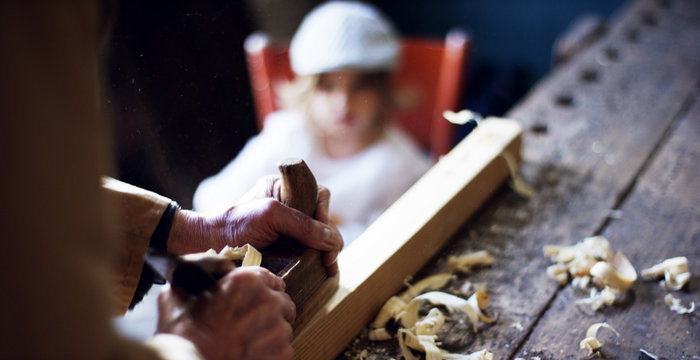 in an old carpentry shop a child and grandfather playing with a wooden airplane concept of tradition that continues over time	