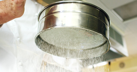 in an Italian professional kitchen a chef pours salt on a dish or in the water to boil the Italian pasta concept of healthy and light food.