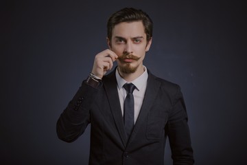 Studio portrait of a serious young businessman wearing a black suit on black background, copy space