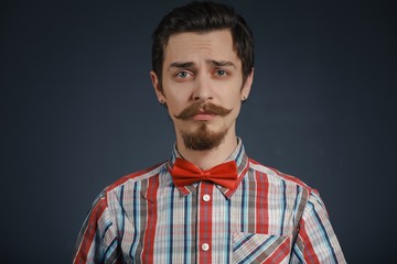 Young caucasian handsome hipster with beard posing in studio on dark background
