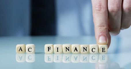 Slow motion macro of the word "Finance" made of the wooden letter blocks . Concept of financial market and future of stock market business.