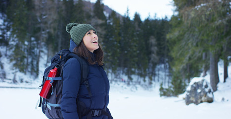 Fototapeta na wymiar slow motion of A girl walks through the woods and in the snow, breathe pure air, smiles in the nature of the mountain, is walking with hiking backpack.Concept:relaxation, hiking, love, purity, freedom