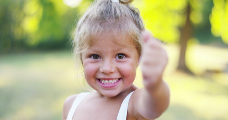 beautiful and healthy baby girl lifts thumb finger in approval. concept approval, nature and sustainability.	