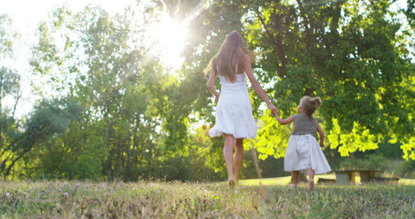 mother with little girls dressed in a vintage lawn walk close to a tree in sunset happy little girl in nature. concept of nature and sustainability, connection with nature and the green world.