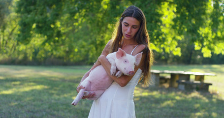 girl caresses and kisses a pig in perfect and green world. sustainability and a love of nature,...