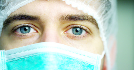 close up portrait of a surgeon or doctor with mask and headset ready for operation in hospital or clinic. The surgeon smiles safe and proud of himself. Concept of medicine, hospitals and doctors, care