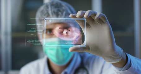 A physician, surgeon, examines a technological digital holographic plate represented the patient's body, the heart lungs, muscles, bones. Concept: Futuristic medicine, the human body, and the future.