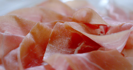 Macro of spinning thin slices of pork ham on the dish (close up)
