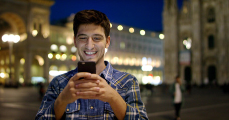 Man look at night in city. Milan italy Handsome young business man using telephone smiling happy wearing wearing blue shirt. Urban male.