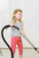 Little beautiful smiling girl running with vacuum cleaner