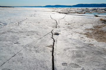 Spring melting of ice on the Volga River against the background of mountains and blue sky
