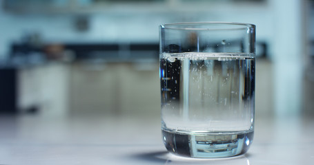 A glass of pure fresh water is poured into a glass, the background kitchen, nature, from which the fresh and pure water. Concept: nature, purification, freshness.