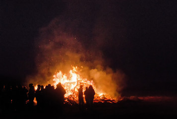 Fototapeta na wymiar large people crowd only visible as silhouettes in front of a large Easter bonfire at night