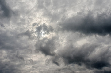 Dramatic stormy clouds shroud the light of the sun creating a multitude of shapes made of light breaking through and shadows it casts