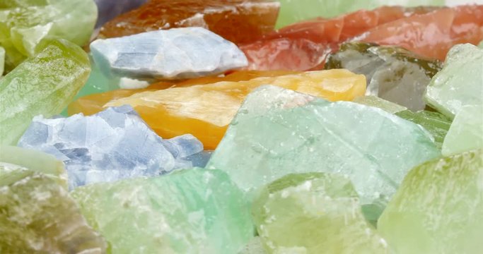 Several multi colored calcite gem stones rotating in close up shot. Large and rough semi precious gemstones. Clip usable as seamless loop.
