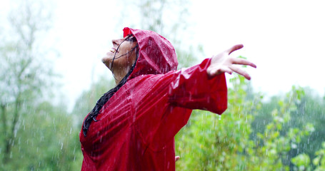 A happy woman smiles in the rain, the woman immersed in the nature of dance under the in slow motion. Concept of love, nature, happiness, freedom.