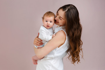 Portrait of a beautiful mother smiling with her 3-month-old child, holding hands, side view
