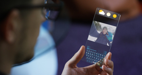 A man in the city, use the transparent phone with the latest technology for video calls with holography family on vacation. Concept: technology, future and futuristic technology, family	