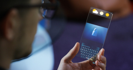 A man in the city, use the transparent phone with the latest technology for video calls with holography family on vacation. Concept: technology, future and futuristic technology, family