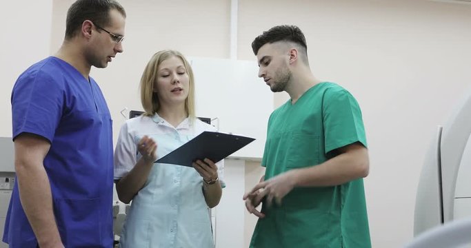 4K Three young doctors in medical suits talking in a clinic.