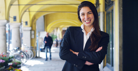 Beautiful career woman looks into camera and smiles, in the background the city.The businesswoman...