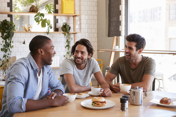 Fototapeta na wymiar Three Male Friends Meeting For Lunch In Coffee Shop