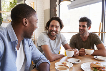 Three Male Friends Meeting For Lunch In Coffee Shop