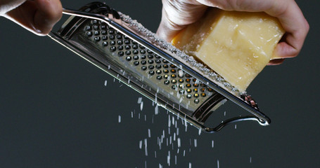 Slow motion of A cook grater Parmesan cheese, typical Italian cheese, on the plate just freshly brewed. Concept: Italian cuisine, cheese, restaurant and food.	
