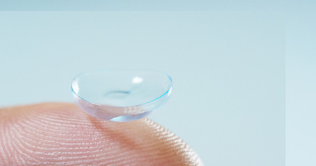 Macro shot of a finger holding a contact lens technology with a chip to see better in both eyes and increase diopters. Concept: eye examination, optical, immersive technology	
