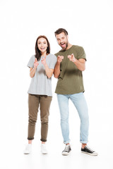 Happy young loving couple standing isolated and pointing.