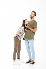 Laughing young loving couple holding phones.