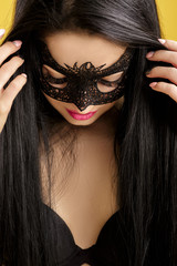 portrait of beautiful sensual woman in black lace mask on yellow background. sexy girl in venetian mask