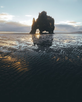 Beach rock formation at sunrise with tiny person