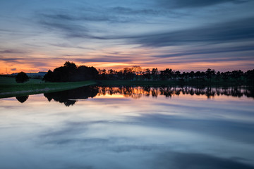 Fototapeta premium Zmierzch w Whittle Dene Reservoir / Whittle Dene Reservoir w Northumberland to popularne miejsce do wędkowania, widziane tutaj o zmierzchu, odbijające niebo