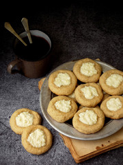 Healthy Peanut Butter Cheesecake Thumbprint Cookies. Delicious homemade shortbread and cup of tea on dark background. Copy space.