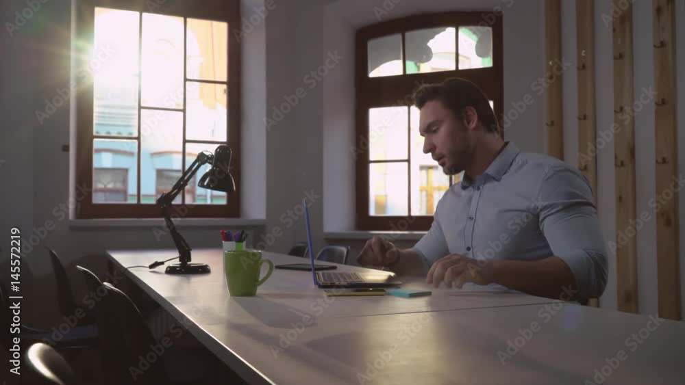 Poster middle aged man working in the office. handsome worker sitting in boardroom alone using smartphone c