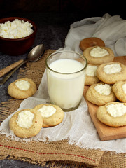 Healthy Peanut Butter Cheesecake Thumbprint Cookies. Delicious homemade shortbread and glass of milk on dark background.