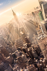 La ville de New York. Le centre-ville de Manhattan avec l& 39 Empire State Building illuminé et les gratte-ciel au coucher du soleil. Composition verticale. Couleurs chaudes du soir. Rayons de soleil et lumière parasite.