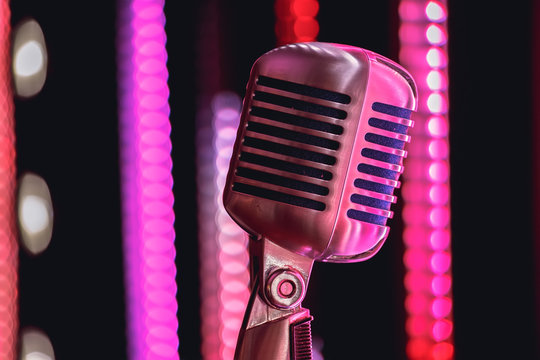 Retro style microphone on stage in the spotlight performance of the musical group. Microphone for rock music. Microphone in blue light og stage. Music is in the air. Color background.