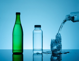 Bottle with creative splashing water in the glass