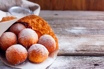 Freshly made donuts from cottage cheese with powdered sugar in a paper bag, copy space
