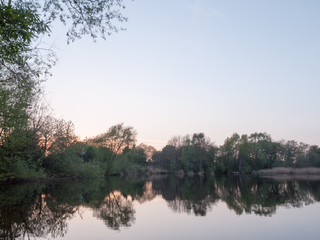 sunsetting over a lake as the trees around are reflected in the water
