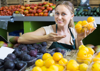 Portrait of young woman selling ripe fresh plums