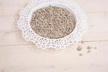 Sunflower seeds in white bowl on wooden background